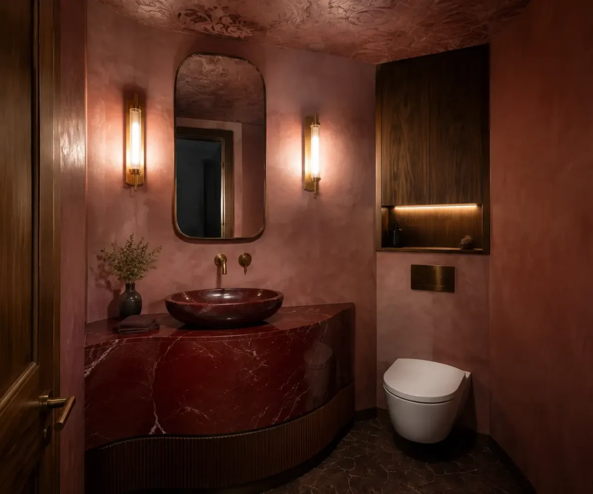 Oxblood powder room with sculptural single basin, toilet and warm wall lights