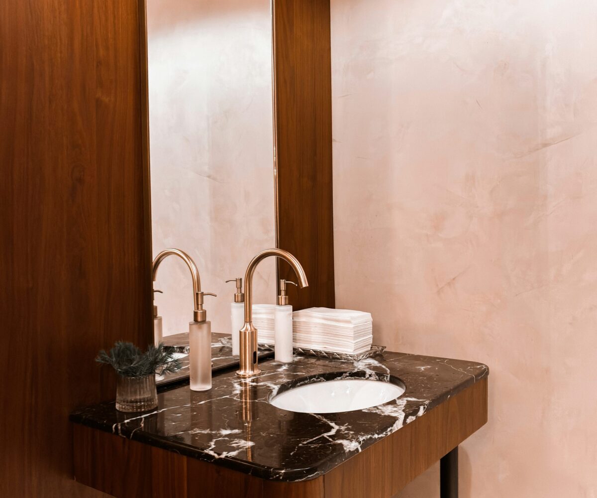 Compact powder room with walnut wall panel, marble counter and brass faucet