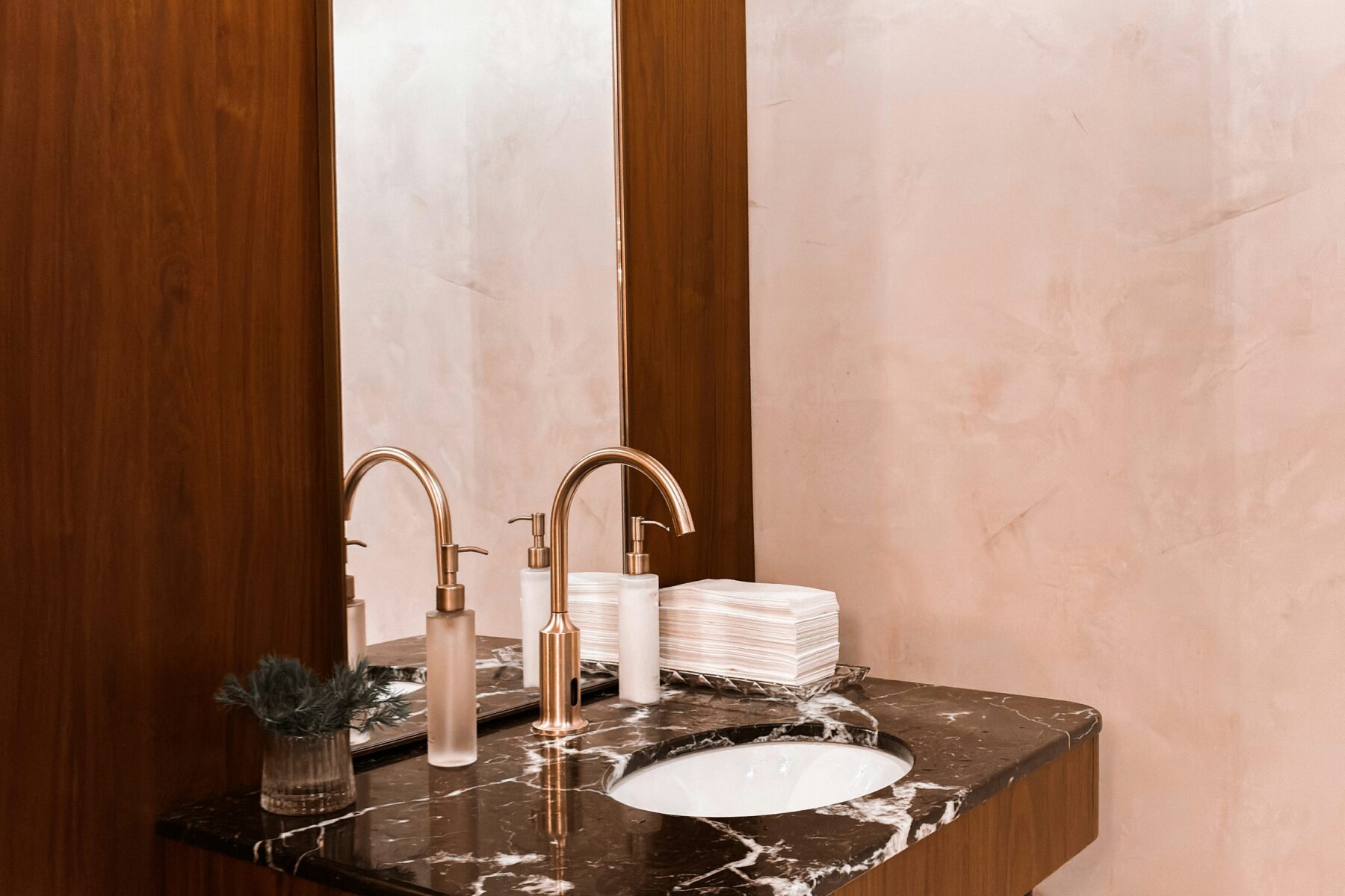 Compact powder room with walnut wall panel, marble counter and brass faucet
