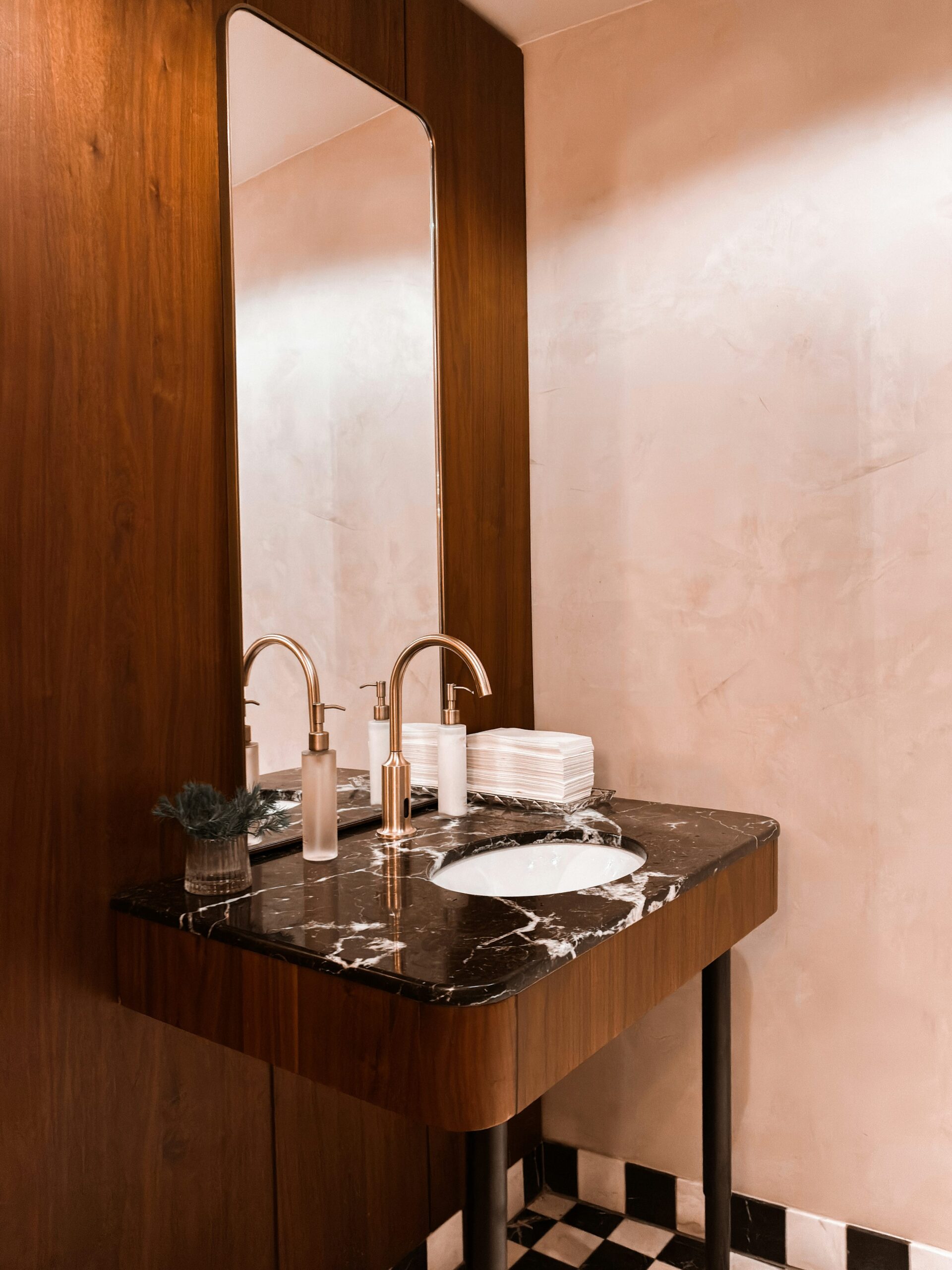 Compact powder room with walnut wall panel, marble counter and brass faucet