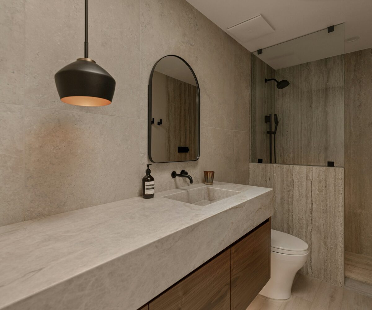 Stone toned bathroom with floating wood vanity and walk-in shower