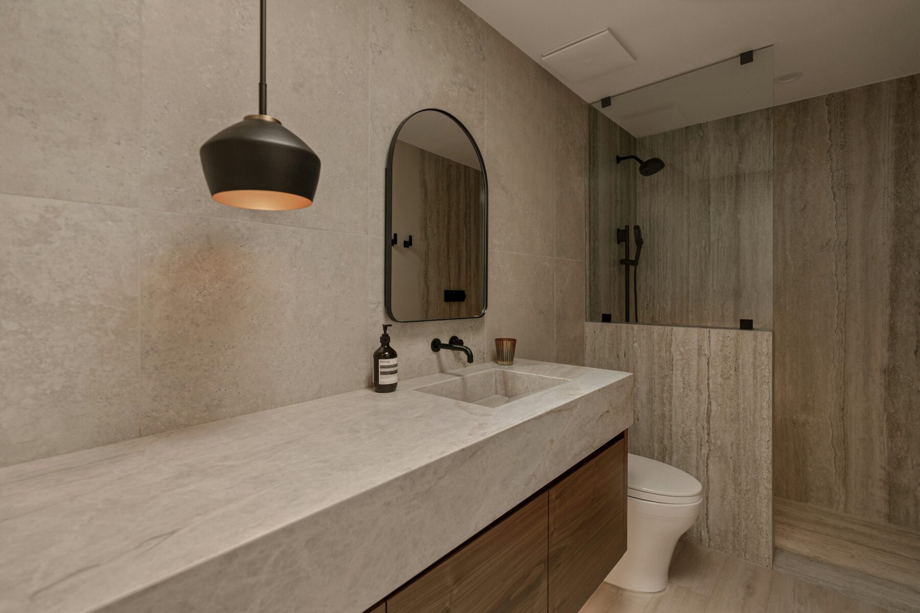 Stone toned bathroom with floating wood vanity and walk-in shower