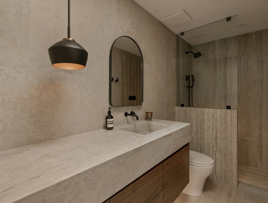 Stone toned bathroom with floating wood vanity and walk-in shower